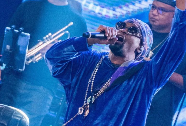 O cantor Toni Garrido, vocalista da banda Cidade Negra, durante uma apresentação ou entrevista, falando sobre a letra da música "Girassol".