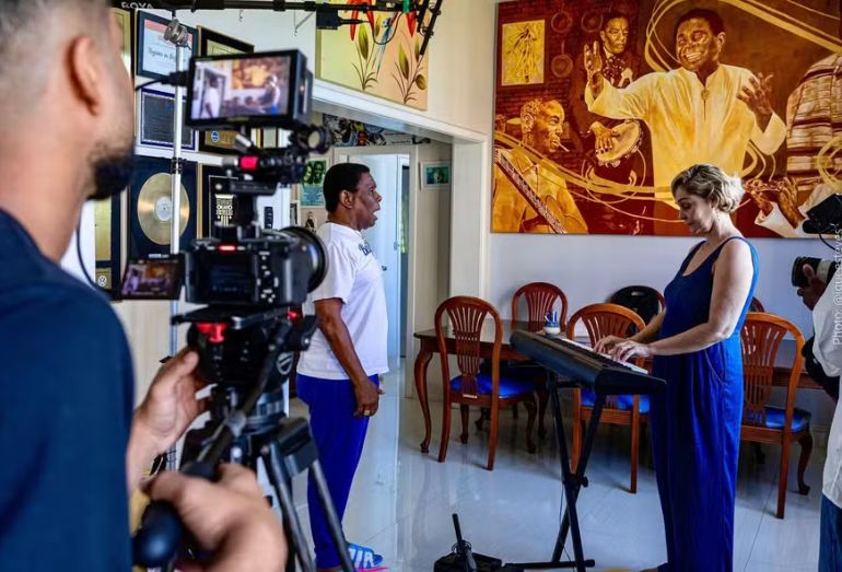 O sambista Neguinho da Beija-Flor, sorrindo e em destaque, em foto promocional de seu documentário.